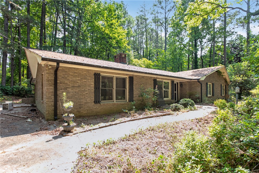 A classic brick exterior offers timeless appeal amidst a lush, wooded backdrop.