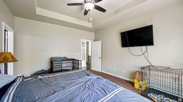 6062 Spring Street Stansbury Park, UT 84074 - Photo 12 of 36 Primary Bedroom, Spacious room featuring a tray ceiling with a ceiling fan, neutral wall paint, and brown carpeting
