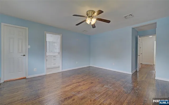 an empty room with wooden floor chandelier fan and windows