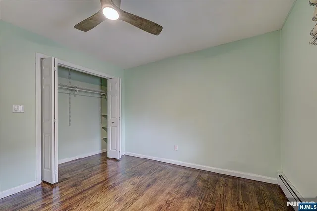 an empty room with wooden floor closet and fan