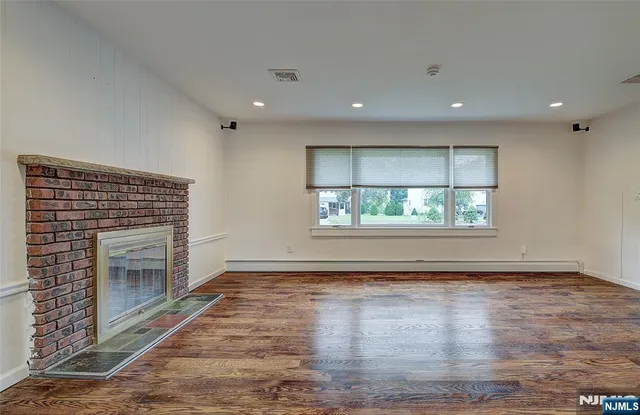 an empty room with wooden floor fireplace and windows