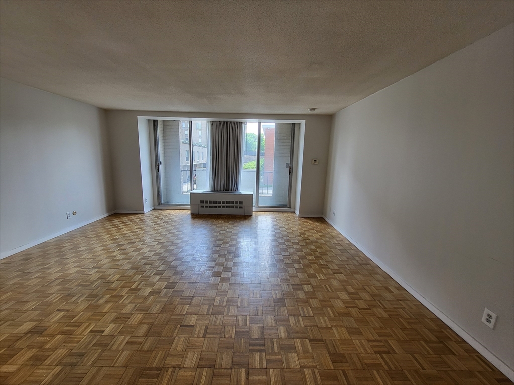 44 Washington Street, Unit 206 Brookline, MA 02445 - Photo 3 of 26 a view of empty room with wooden floor and fan