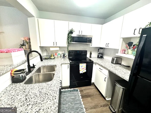 a kitchen with kitchen island granite countertop a sink stove and cabinets