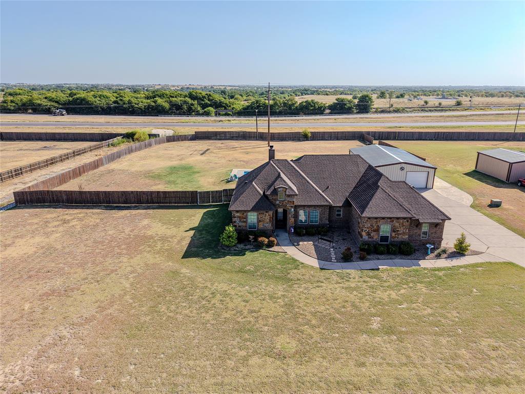 123 Cactus Drive Decatur, TX 76234 - Photo 2 of 30 Stone and brick exterior with a dark shingle roof, concrete driveway, attached metal structure, and fenced perimeter