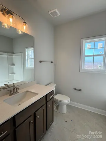 a bathroom with a granite countertop sink a toilet and a mirror