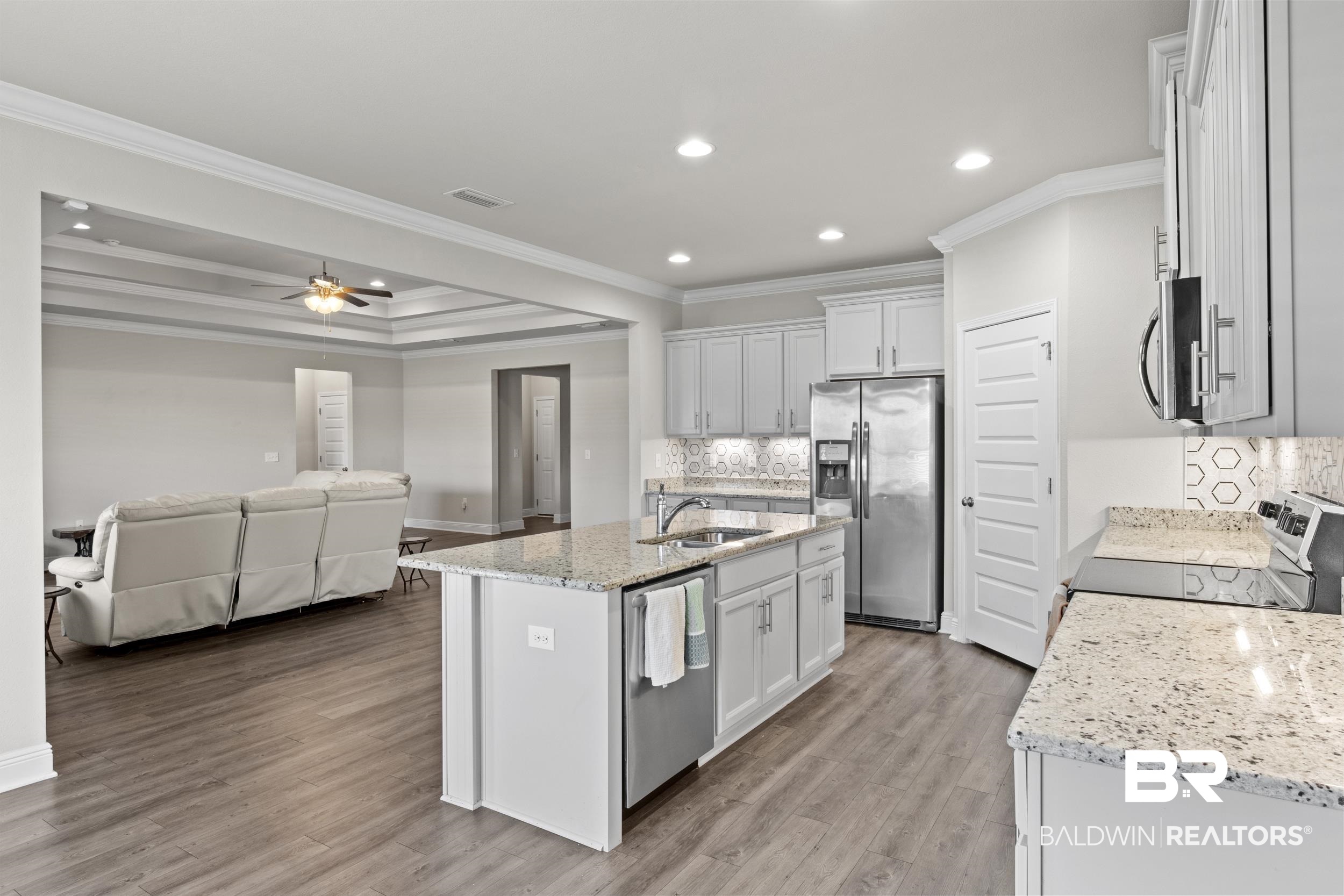 2050 Bourbon Street Foley, AL 36535 - Photo 12 of 32 Kitchen featuring a center island with sink, ornamental molding, light hardwood / wood-style floors, white cabinetry, and stainless steel appliances