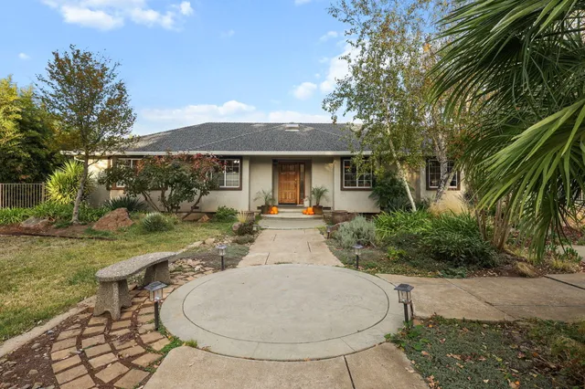 a open kitchen with stainless steel appliances granite countertop a stove a refrigerator a oven a dining table and chairs with wooden floor