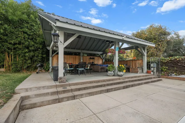 a view of a patio with table and chairs a barbeque with plants and trees