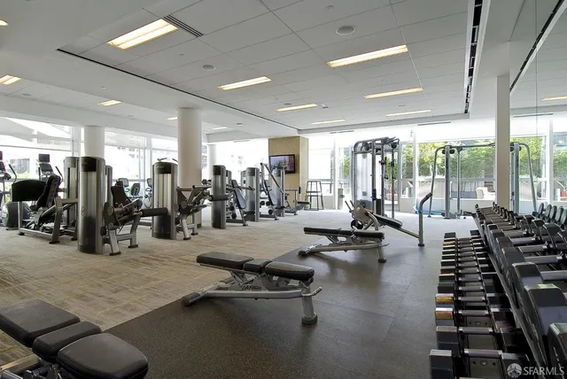 a gym room with lots of gym equipment and a large window