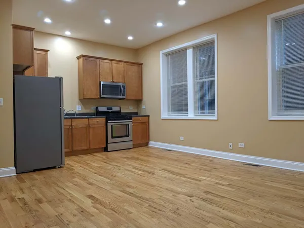 a view of kitchen with kitchen island stainless steel appliances wooden floor and window