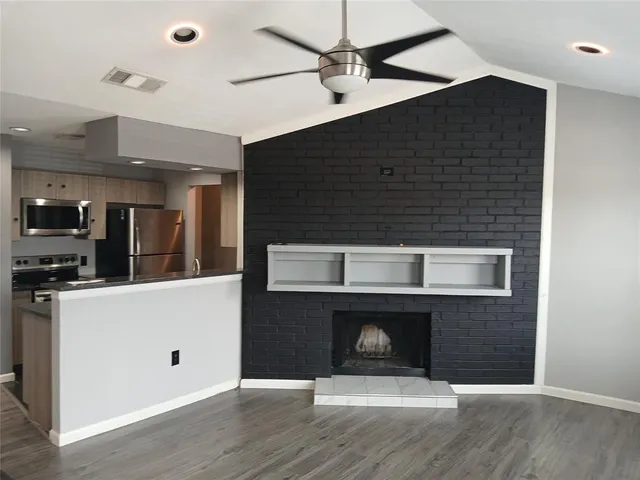 a living room with stainless steel appliances wooden floor and chandelier