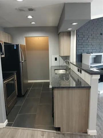 a kitchen with stainless steel appliances granite countertop a sink and a refrigerator