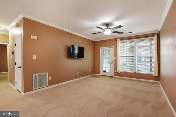 a view of an empty room with chandelier fan and a large window