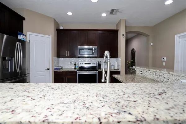 a kitchen with stainless steel appliances kitchen island granite countertop a refrigerator and a sink