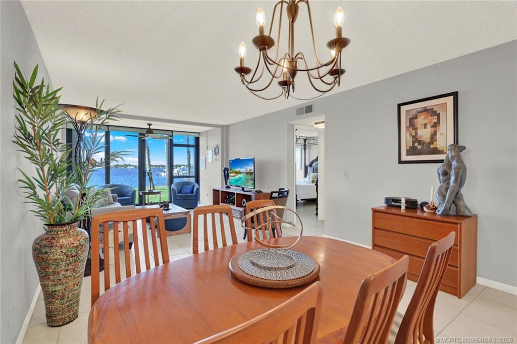 1950 Southwest Palm City Road, Unit 8106 Stuart, FL 34994 - Photo 15 of 54 a dining room with furniture a rug a potted plant and a chandelier