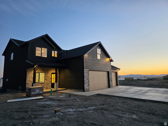 1267 West 2350 South Perry, UT 84302 - Photo 6 of 35 Two-story residence featuring a dark siding exterior with stone accents, a covered entry, and a two-car garage with concrete driveway