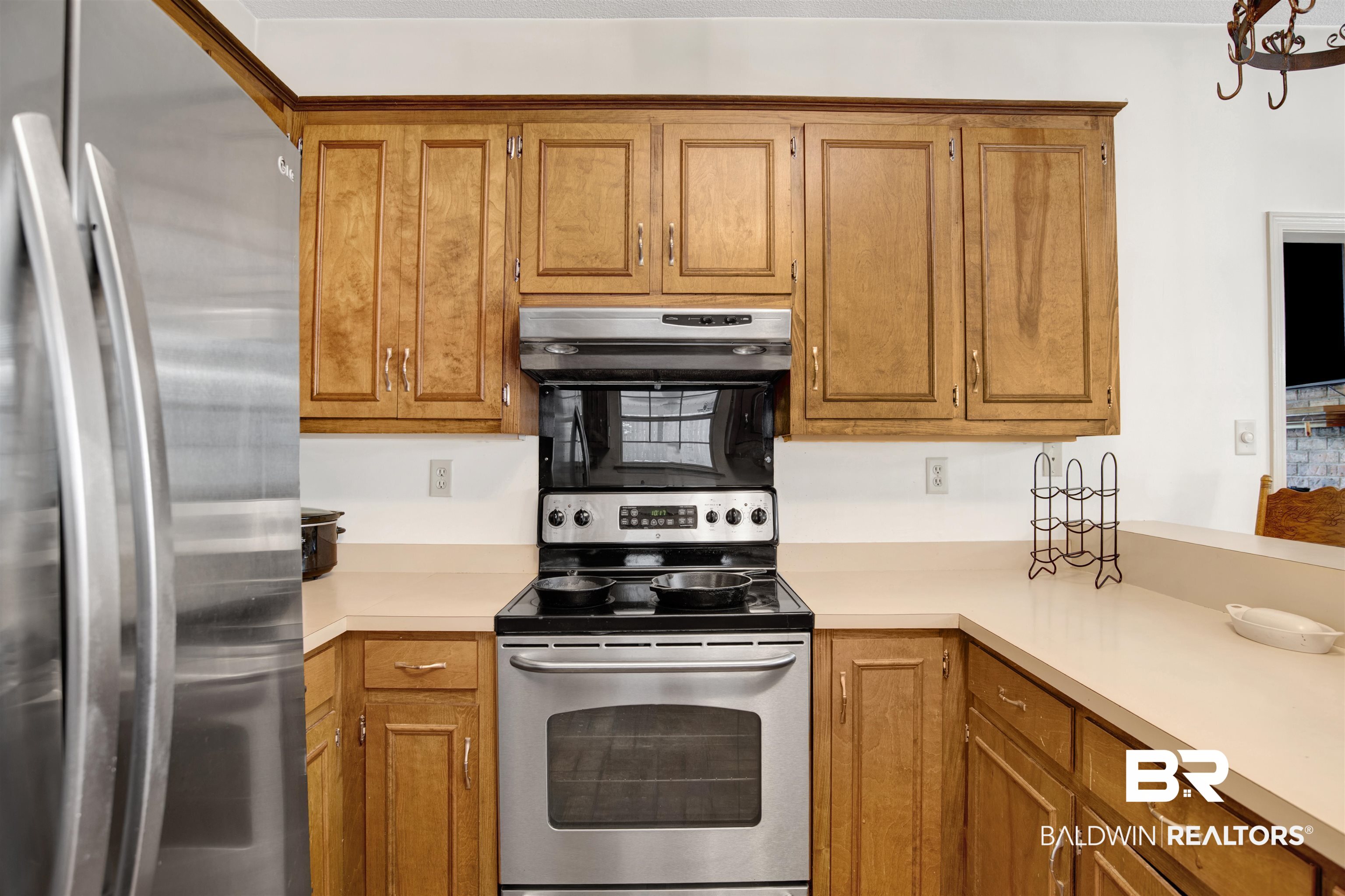 3412 Peyton Court Mobile, AL 36695 - Photo 13 of 27 Kitchen featuring appliances with stainless steel finishes, extractor fan, light countertops, and brown cabinetry