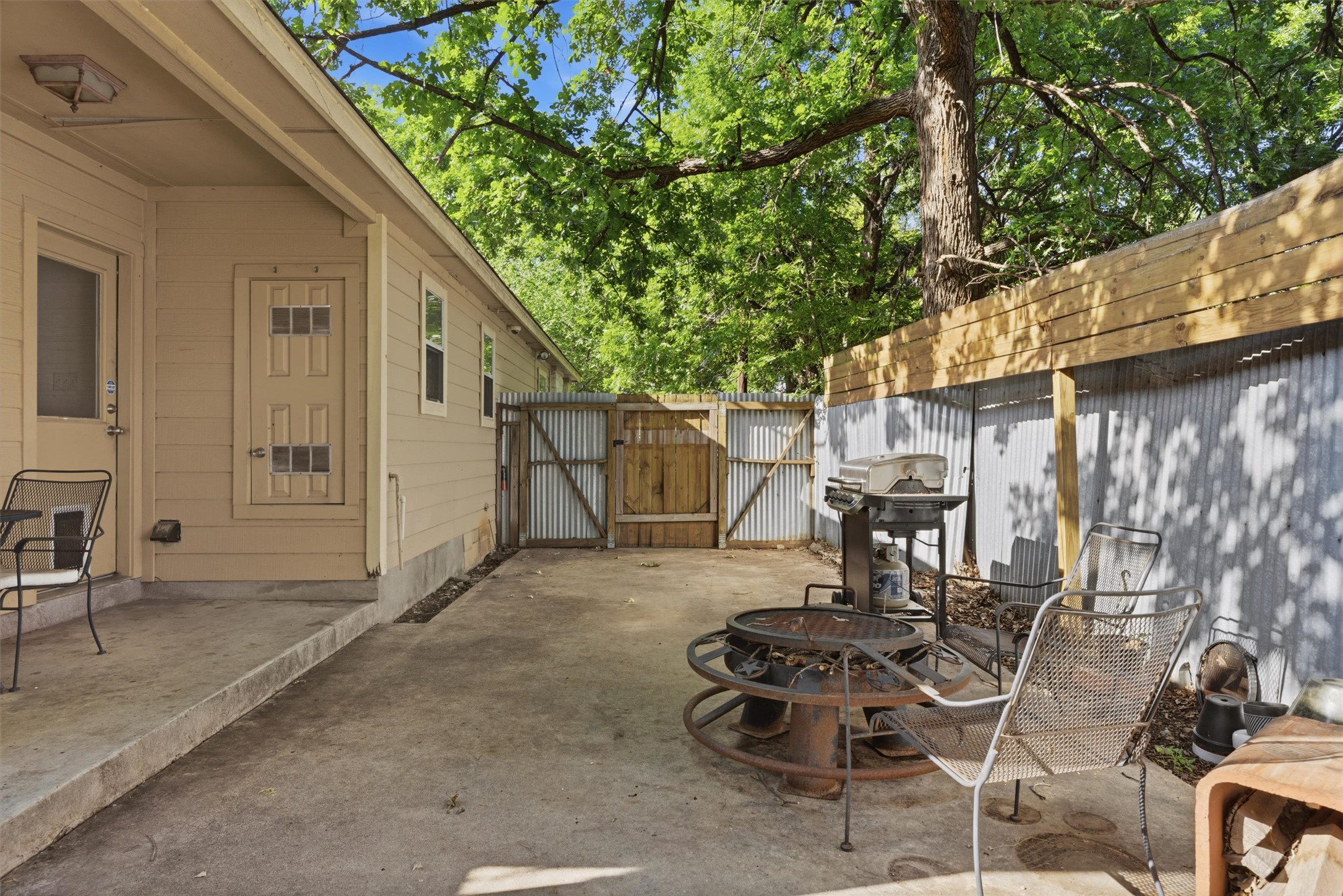 3015 Castro Street Austin, TX 78702 - Photo 29 of 40 A private outdoor space with a corrugated fence and mature shade trees, ideal for casual gatherings.