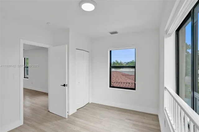 a view of a hallway with wooden floor and closet