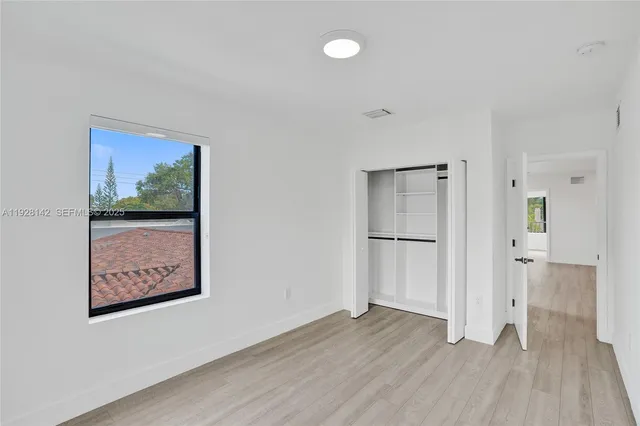 a view of a hallway with wooden floor and closet