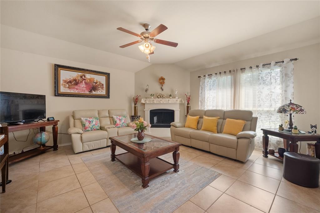 520 Rustic Oak Lane McKinney, TX 75072 - Photo 20 of 30 Living area featuring vaulted ceilings, a ceiling fan, tiled flooring, and a corner fireplace with a mantel