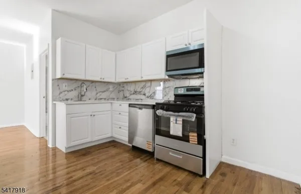 a kitchen with stainless steel appliances a stove a microwave and white cabinets