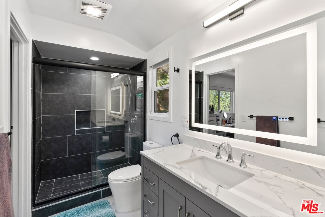 4118 Oak Hollow Road Calabasas, CA 91302 - Photo 46 of 55 a bathroom with a granite countertop sink a toilet a mirror and shower