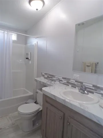 a bathroom with a granite countertop toilet a sink and shower