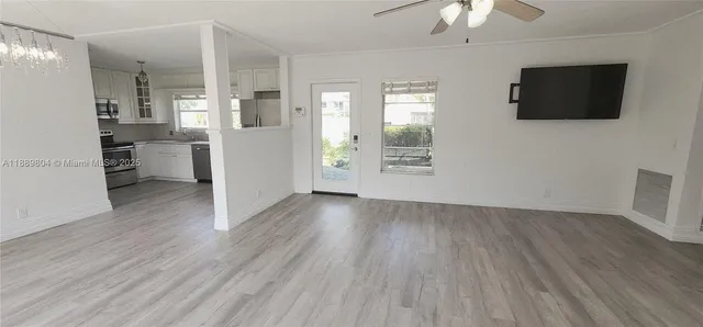 a view of a livingroom with a flat screen tv wooden floor and a kitchen