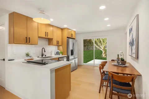 a kitchen with a refrigerator a stove a sink dishwasher with a dining table and chairs