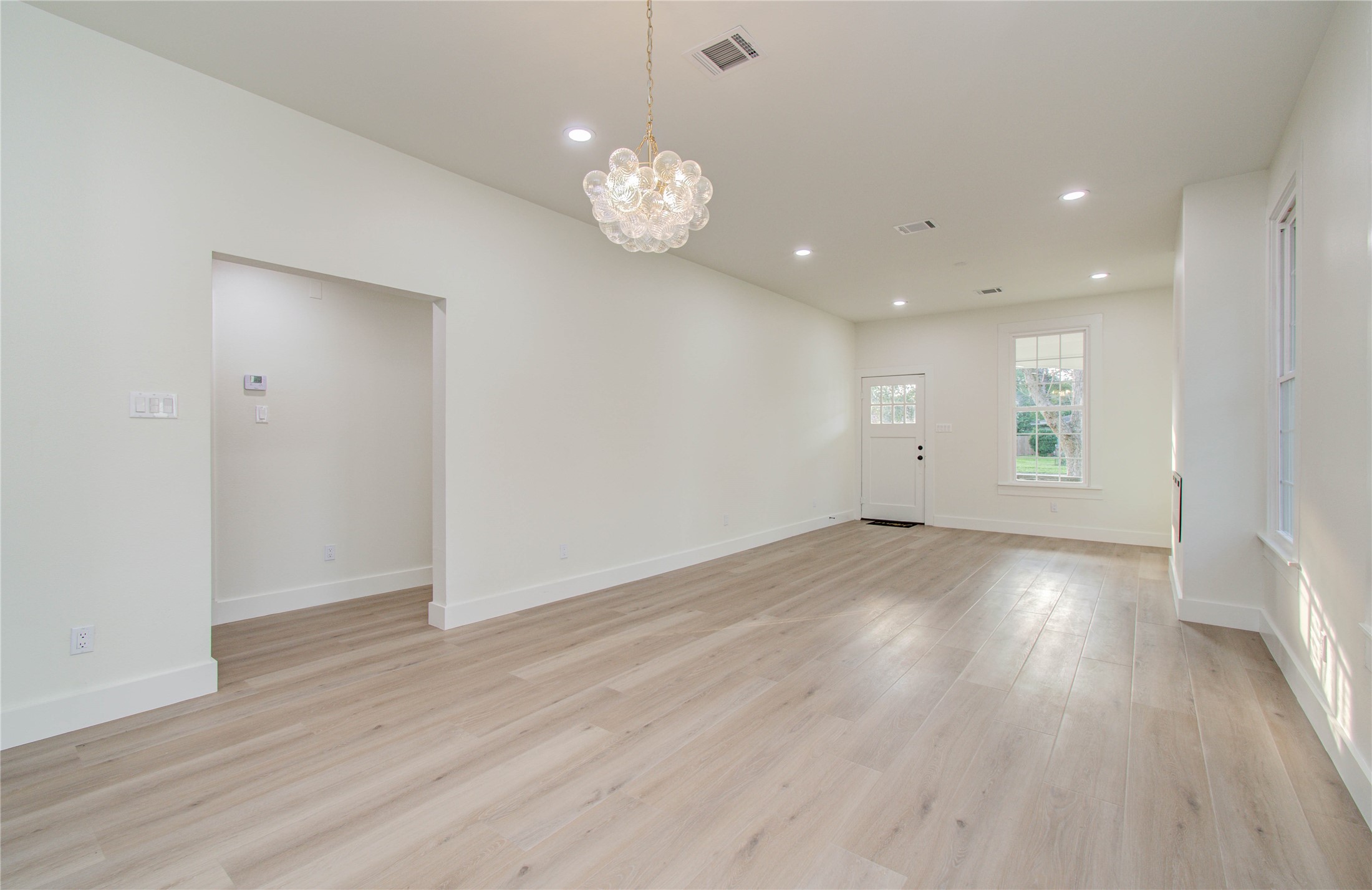 727 Travis Street Columbus, TX 78934 - Photo 11 of 36 an empty room with wooden floor and windows