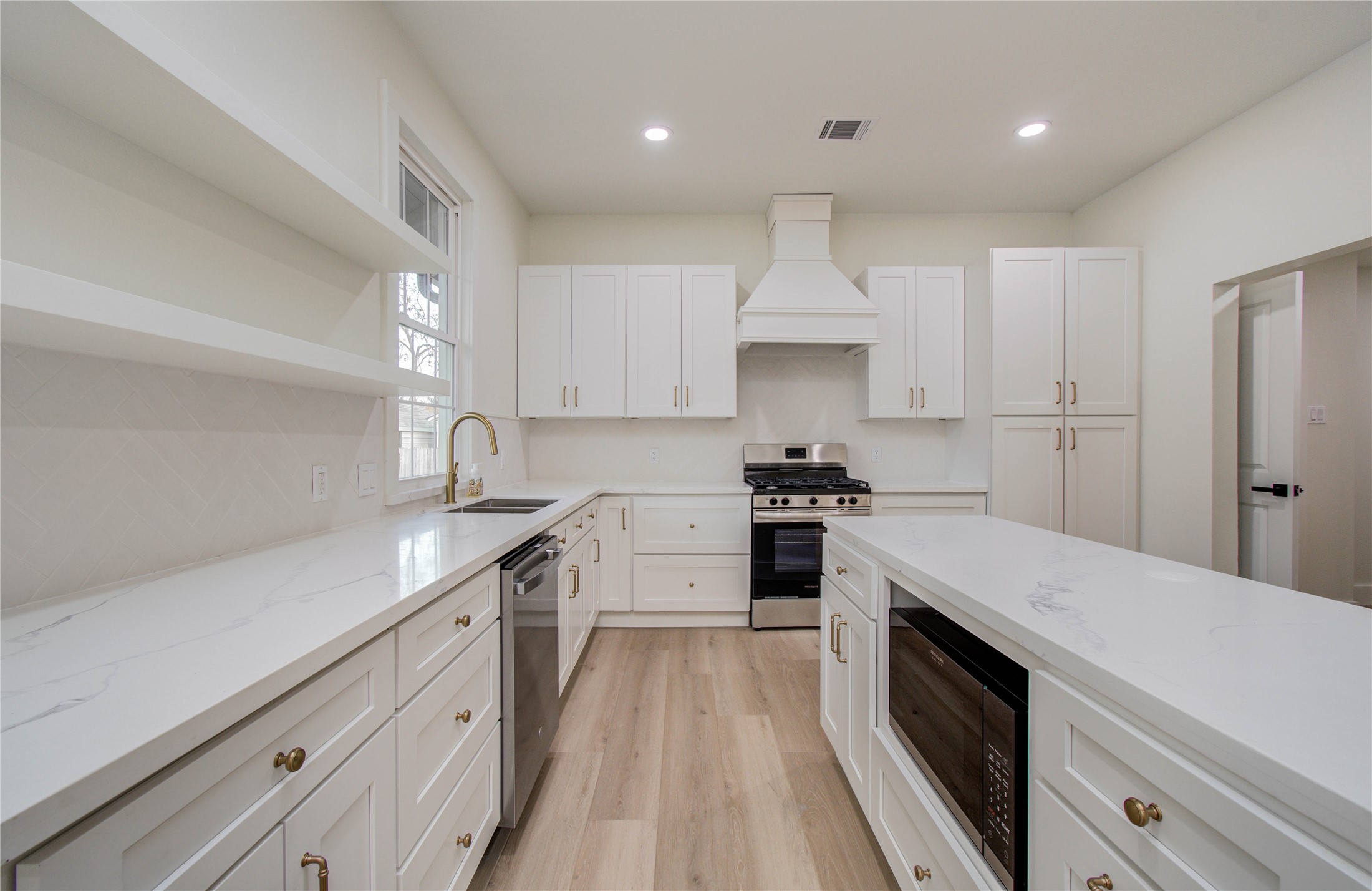 727 Travis Street Columbus, TX 78934 - Photo 13 of 36 Ample countertop space for prep! Neutral quartz countertops, herringbone style backsplash, custom vent hood and warm brass finishes add such a timeless yet modern feel to the kitchen space