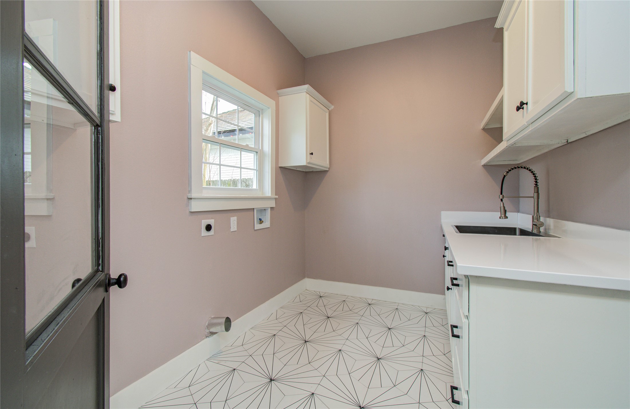 727 Travis Street Columbus, TX 78934 - Photo 31 of 36 Just outside the backdoor in the covered carport, the laundry room is complete with central air & heat. It offers functional design with storage and a utility sink.