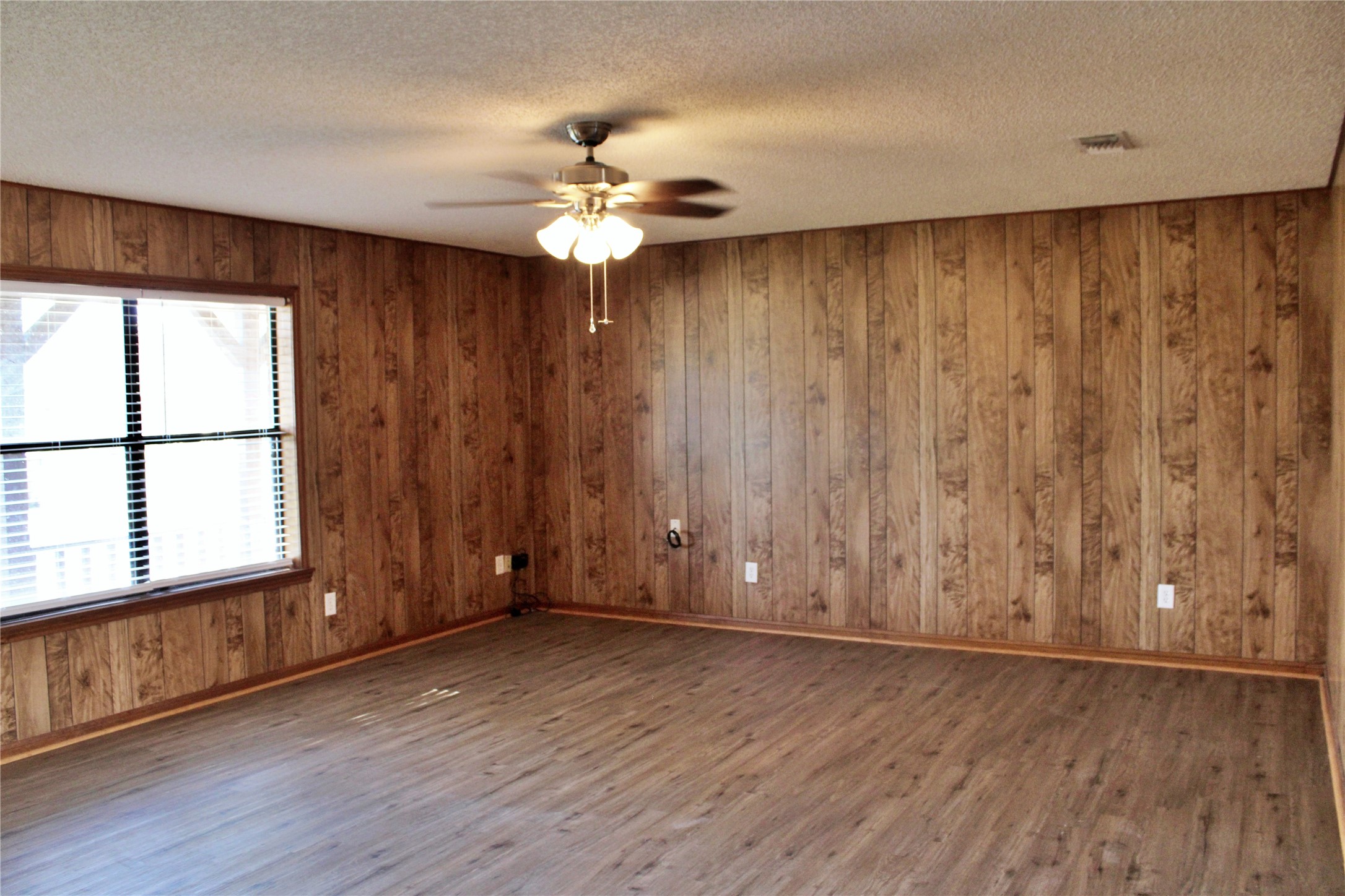 1126 Jackson Street Columbus, TX 78934 - Photo 3 of 40 an empty room with wooden floor chandelier fan and windows
