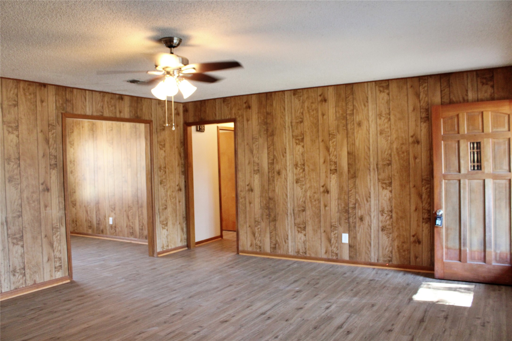 1126 Jackson Street Columbus, TX 78934 - Photo 4 of 40 an empty room with wooden floor chandelier fan and windows