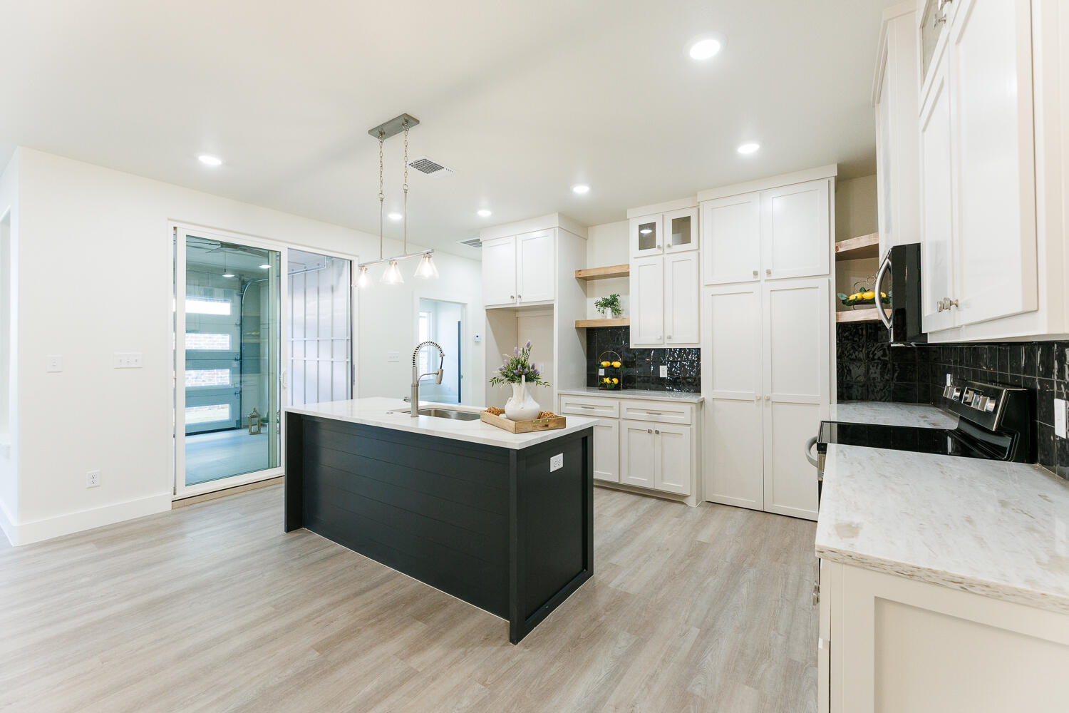 3819 58th Street Lubbock, TX 79413 - Photo 16 of 63 a kitchen with stainless steel appliances kitchen island granite countertop a refrigerator a stove a sink and white cabinets with wooden floor