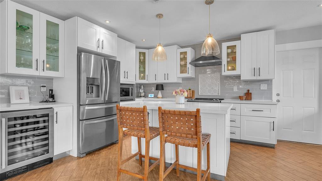 2800 Northeast 53rd Street Lighthouse Point, FL 33064 - Photo 5 of 34 a kitchen with granite countertop a refrigerator oven a sink dishwasher and white cabinets with wooden floor