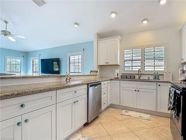 a kitchen with granite countertop sink window and white stainless steel appliances