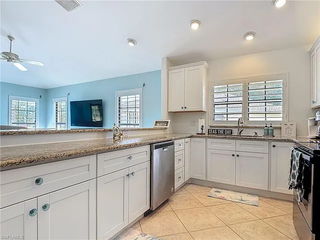 a kitchen with granite countertop sink window and white stainless steel appliances