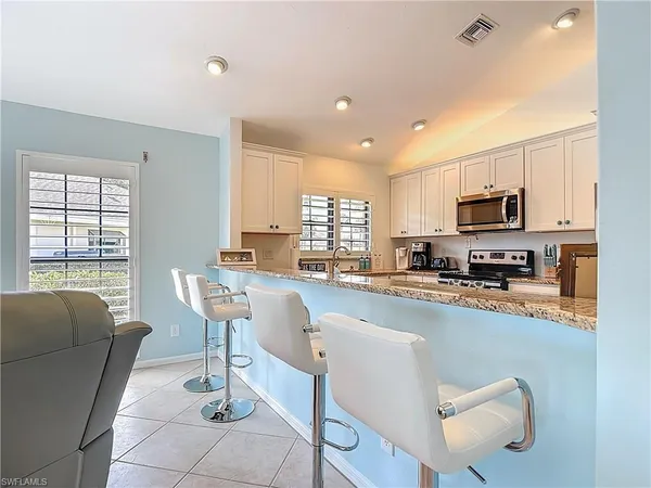 a kitchen with stainless steel appliances granite countertop a dining table chairs microwave and sink
