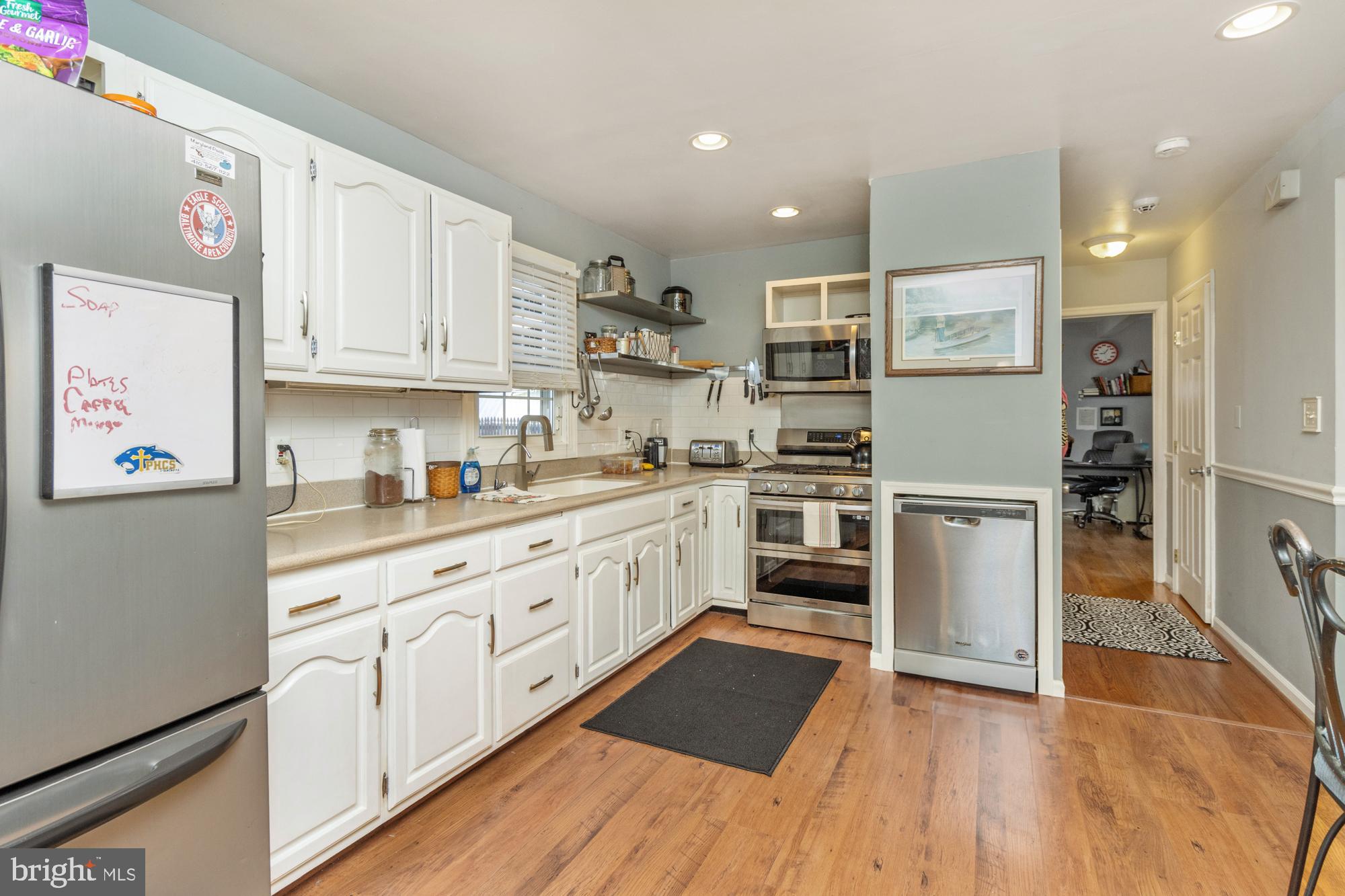 944 Homberg Avenue Baltimore, MD 21221 - Photo 16 of 50 a kitchen with stainless steel appliances granite countertop a stove top oven a sink dishwasher and a refrigerator with wooden floor