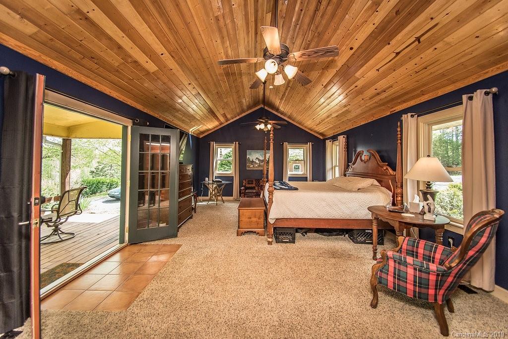 435 Landrum Road Columbus, NC 28722 - Photo 7 of 22 a spacious bedroom with a bed and a chandelier