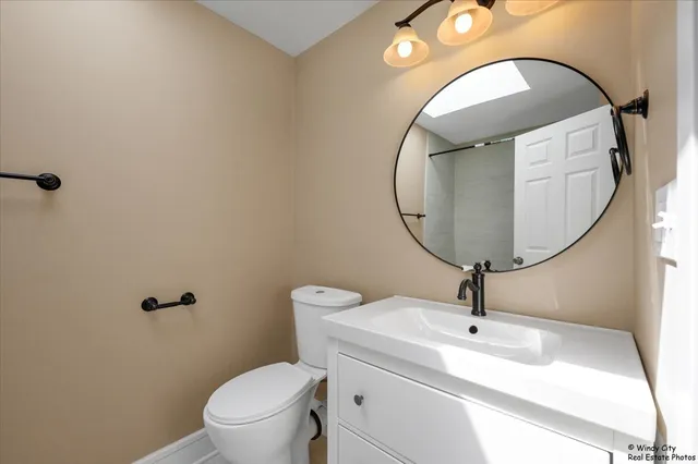 a bathroom with a toilet mirror and vanity