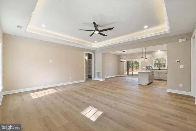 an empty room with wooden floor a ceiling fan and windows