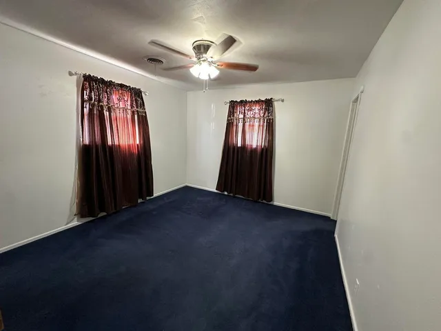 an empty room with a ceiling fan and a window