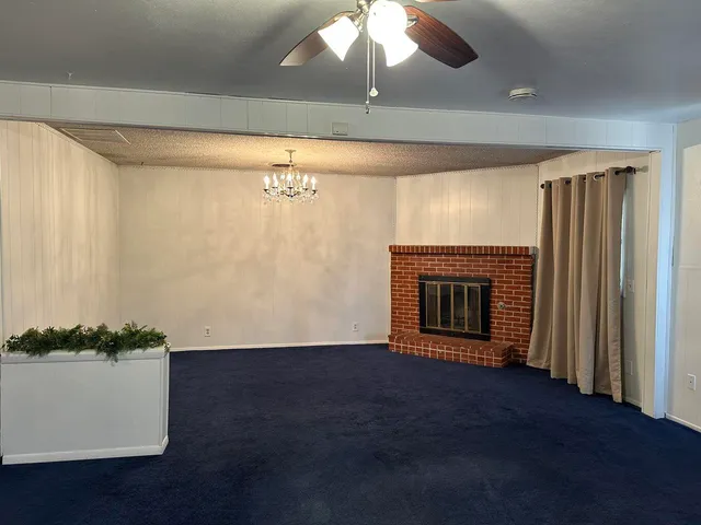 an empty room with wooden floor fireplace and windows