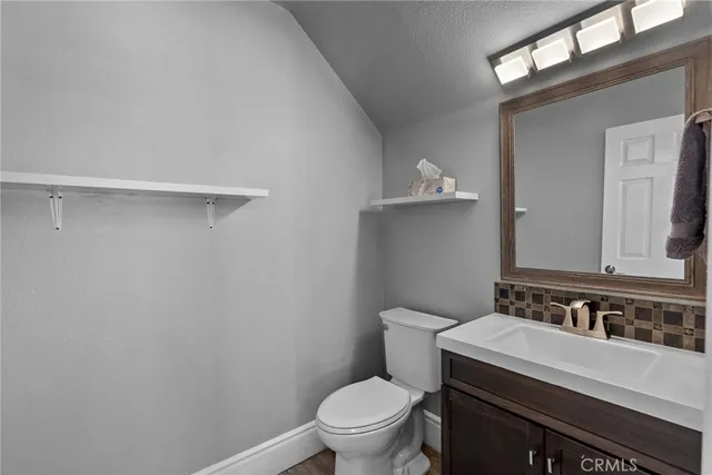 a bathroom with a granite countertop sink a toilet and a mirror
