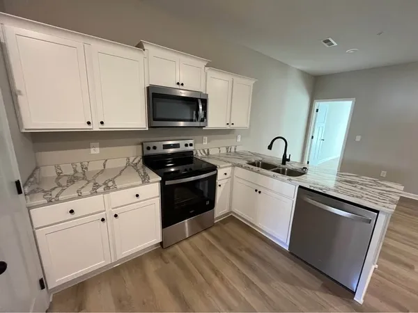 a kitchen with granite countertop white cabinets and black appliances