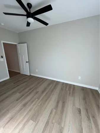 an empty room with wooden floor fan and windows