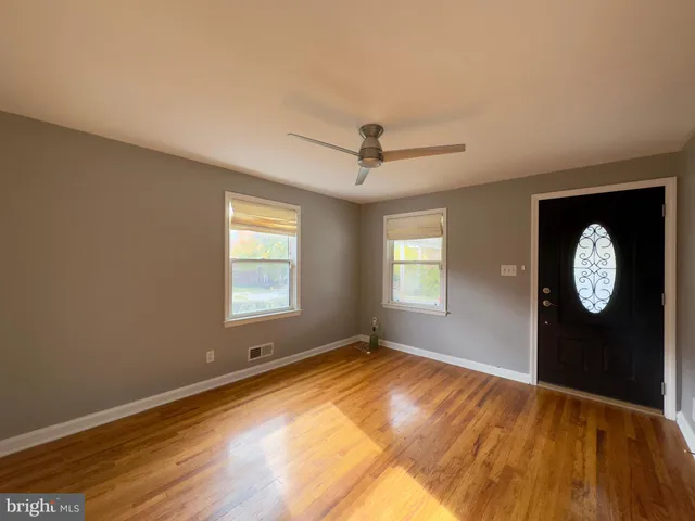 a view of an empty room with window and wooden floor